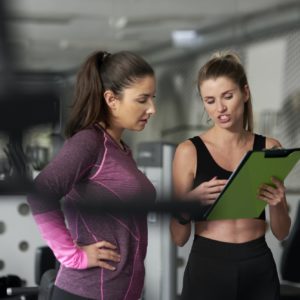 Personal trainer guiding young woman